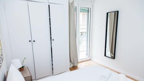 Une chambre d’hôtel avec un lit, une armoire, un miroir et une vue sur l’extérieur.