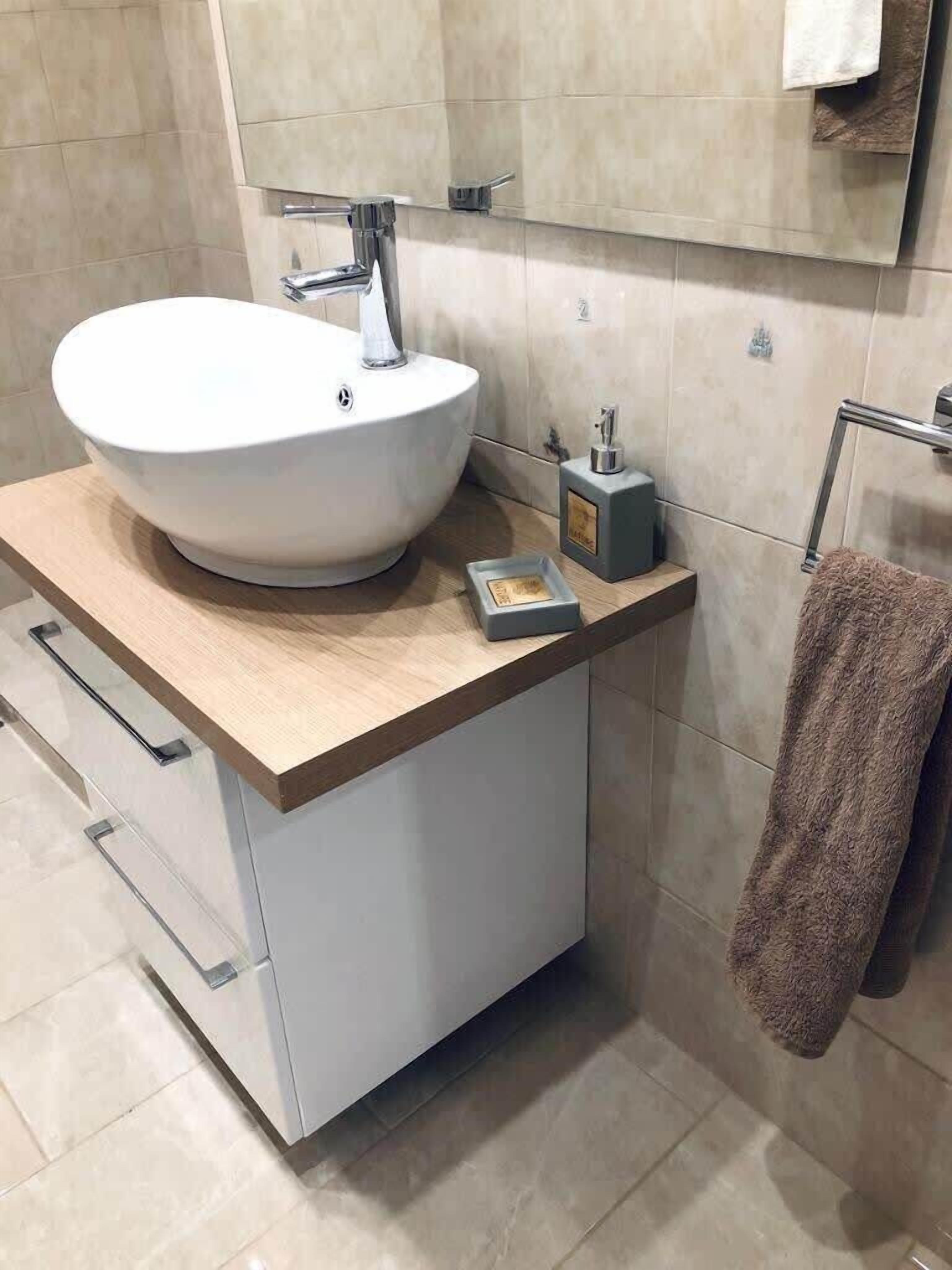 Un baño moderno con un lavamanos de pedestal, un espejo y un perchero para toallas.