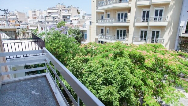 A balcony with a view of a densely planted tree and adjacent buildings. - Piraeus 1 Bd Cosy Apt with Balcony (Athens)