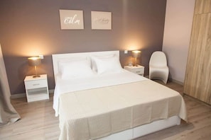 Une chambre bien rangée, avec un grand lit, des tables de chevet et une chaise.