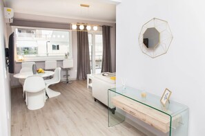 A modern kitchen with white appliances, a dining area with white chairs, and a glass coffee table. - Modern Luxury Central Acropolis View Penthouse (Athens)