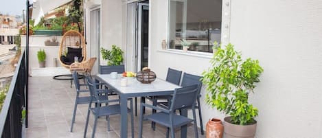 Ein Balkon mit Esstisch, Stühlen und Topfpflanzen.