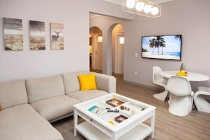 Un salon moderne comprenant un canapé, une table basse et un coin repas avec des chaises et un téléviseur.
