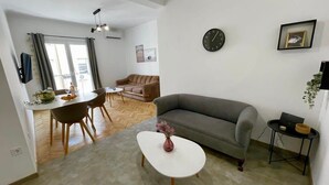 Ein modernes Wohnzimmer mit einem grauen Sofa, einem weißen Couchtisch und einem Essbereich mit Tisch und Stühlen.