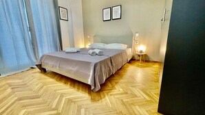 Ein Schlafzimmer mit einem Bett, Nachttischen und einem Parkettboden mit Fischgrätmuster.