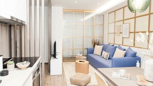 Uma sala de estar moderna com um sofá azul, uma mesa de centro e uma área de cozinha com fogão e pia.