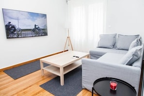 A modern living room with a sofa, a coffee table, a TV mounted on the wall, and a framed picture.