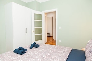 Een slaapkamer met een bed, een garderobe met glazen deuren en een deur naar een andere kamer.