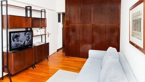 A modern living room with a wooden TV stand, a sofa, and a large wardrobe. - Delux Apartment with Amazing Balcony! (Athens)