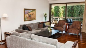 A living room with a grey sofa, two armchairs, a coffee table, and a painting on the wall. - Delux Apartment with Amazing Balcony! (Athens)