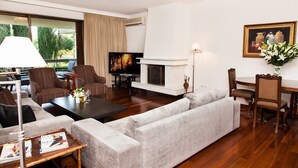 A modern living room with a sofa, armchairs, a coffee table, a fireplace, a television, and a dining area. - Delux Apartment with Amazing Balcony! (Athens)
