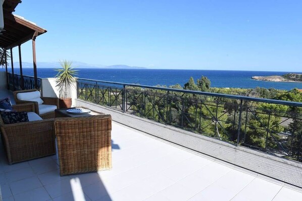 Un balcon doté de meubles en osier et offrant une vue sur la mer.