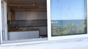 A modern kitchen with white cabinets and a wooden countertop, overlooking a scenic landscape. - Top floor 3bed 2bath with stunning 360 view (Athens)