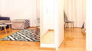 En moderne stue med sofa, stole, sofabord og et mønstret tæppe.