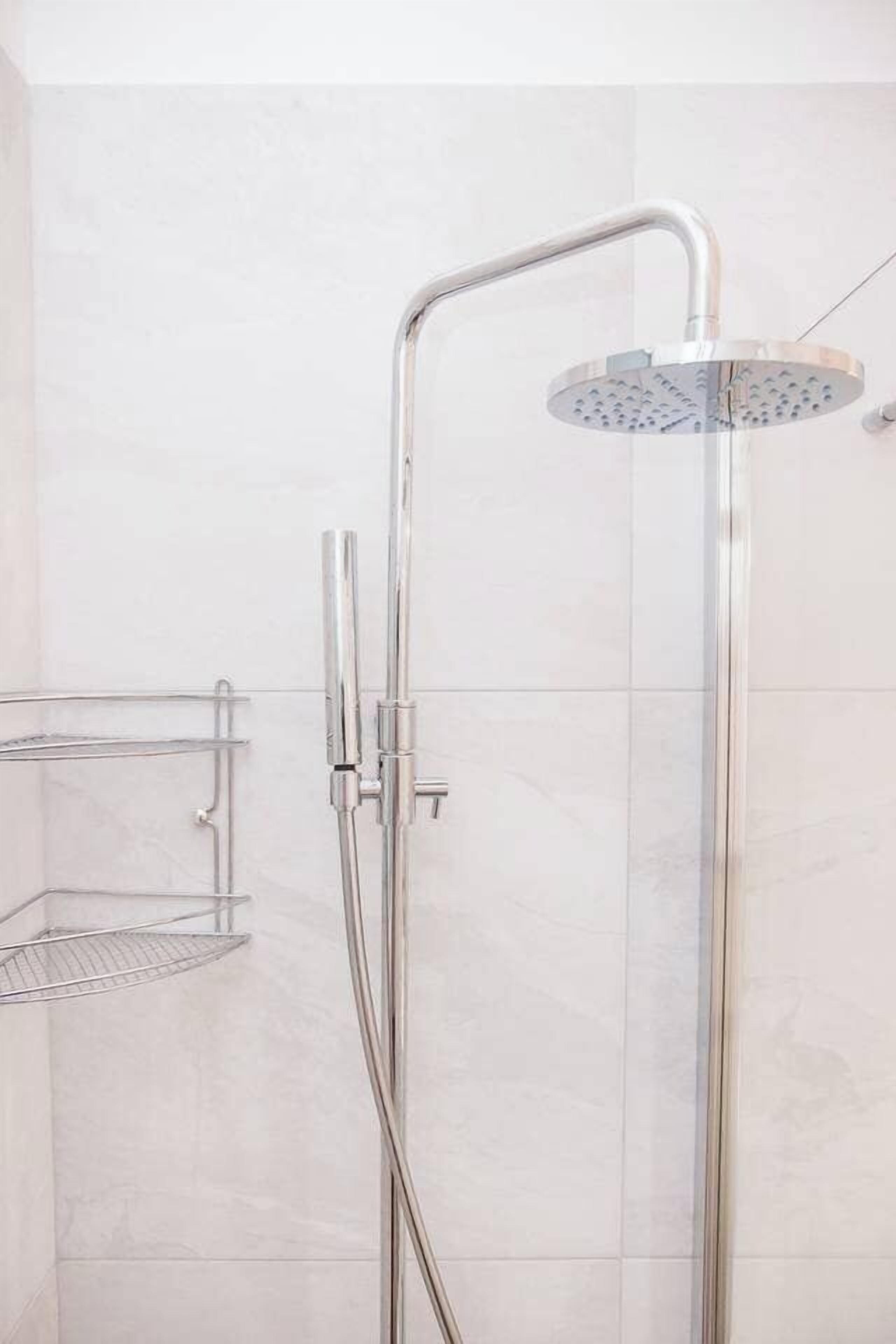Een moderne douche met een handdouche en een wandmengkraan.