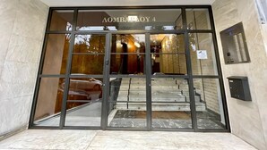 A hotel entrance with a glass door, a staircase leading inside, and a sign above the door.