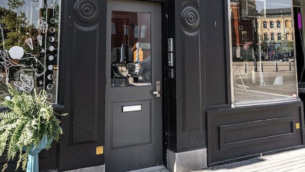 A black storefront with a glass door and windows, a sign that reads "STU", and a small plant outside. - Gateway Inn: Cora's Loft (Stratford)
