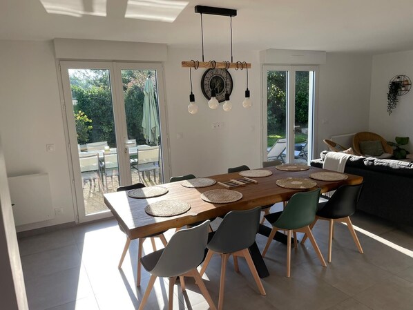 A modern dining area with a wooden table, woven placemats, and contemporary chairs. - New: House, fully renovated, with a garden, 200 meters from the beach - 3*** French property (Loctudy)