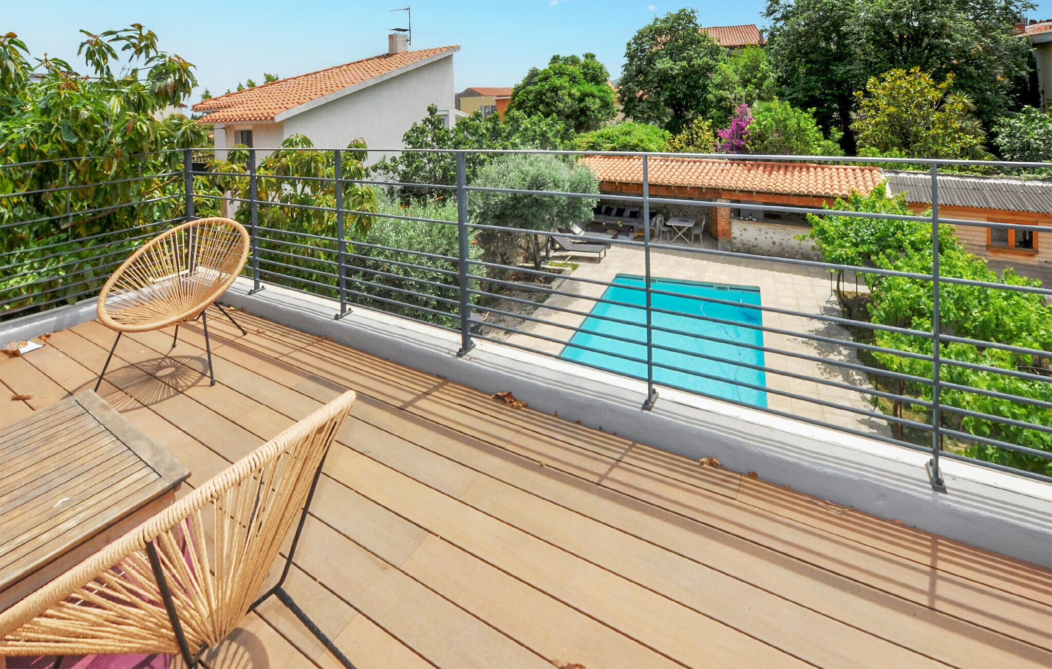 A wooden deck with a pool, a wicker chair, and a table.