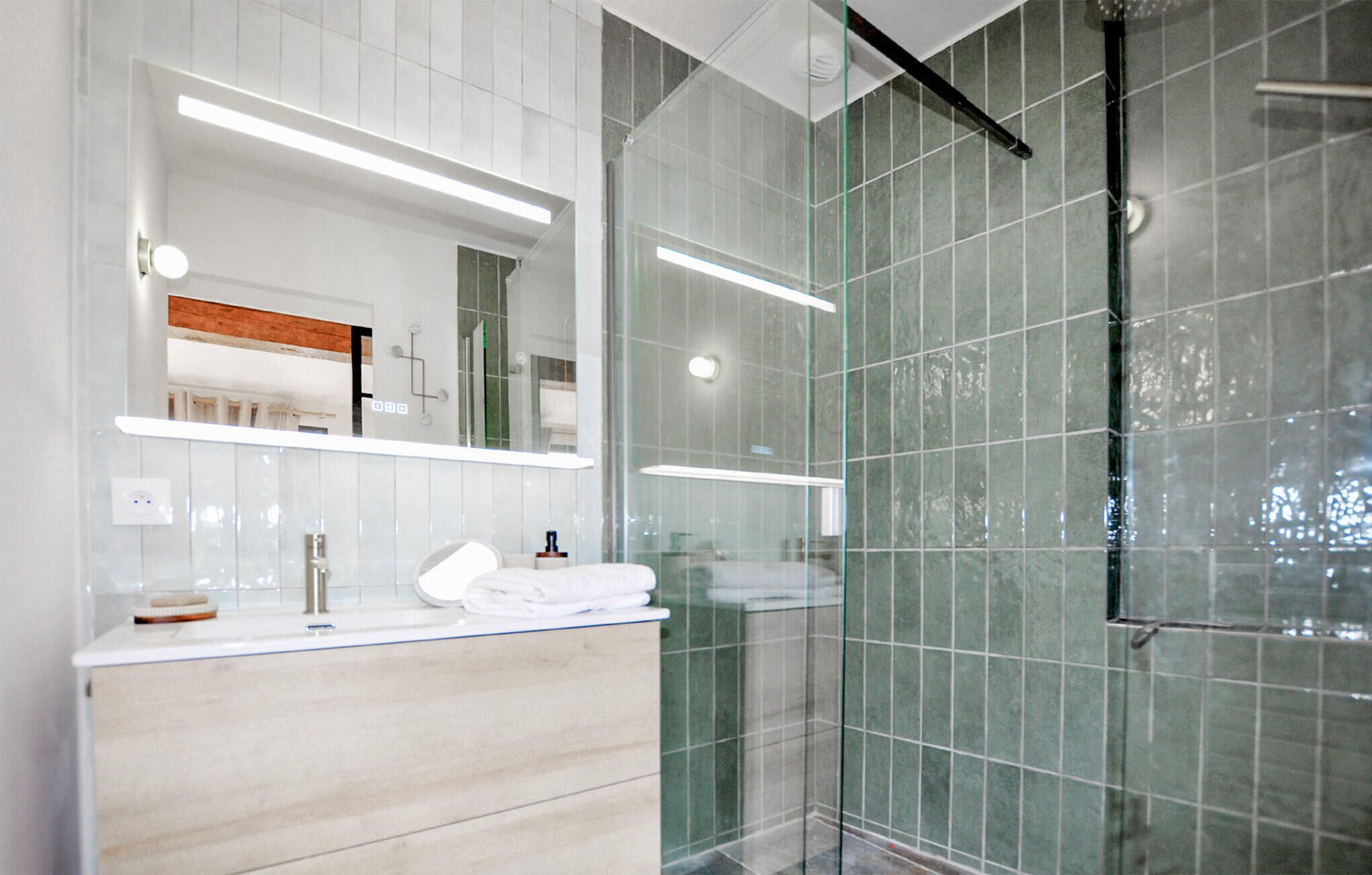 A modern bathroom with a glass shower enclosure, a white vanity with a mirror, and a wooden countertop.