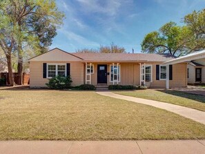 A single-story house with a front porch, a lawn, and a driveway.