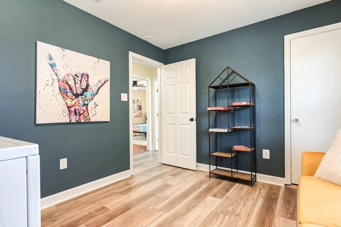 Un corridoio con una porta bianca, una libreria e un quadro astratto colorato appeso al muro.