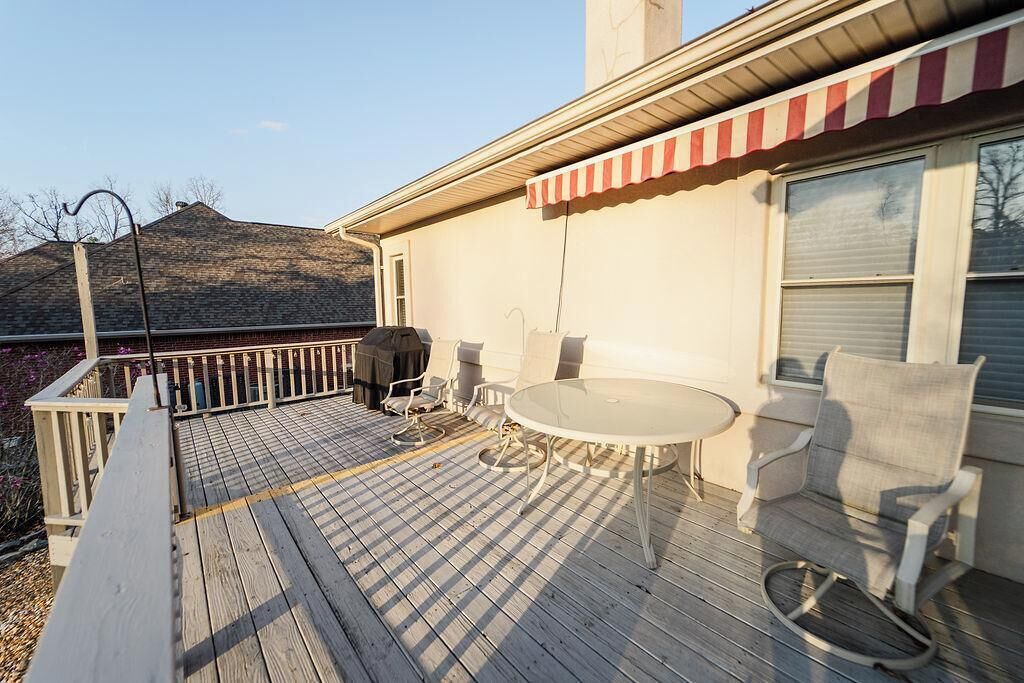 Eine Holzterrasse mit Tisch und Stühlen, ein überdachter Patio-Bereich und Blick auf einen Berg.