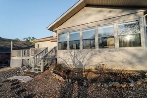 A modern house with a covered porch, a staircase, and a gravel driveway.