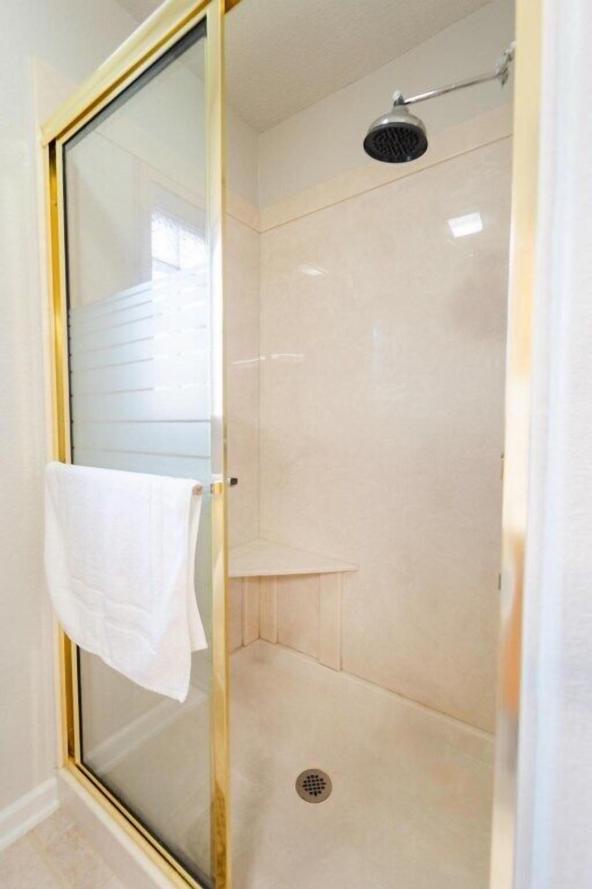 A glass-enclosed shower with a white towel hanging on the door.