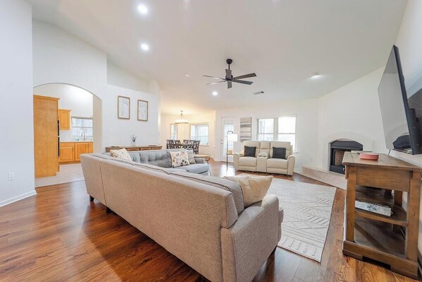 A spacious living room with a large sofa, a fireplace, and a television.