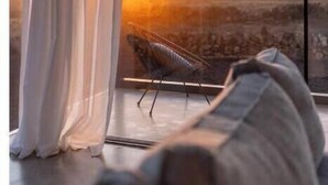 Una habitación moderna con un ventanal grande, una silla y un sofá.