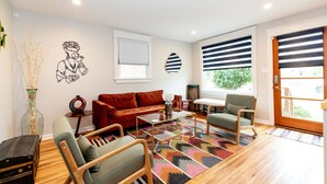Un salon moderne avec un canapé rouge, une table basse en verre et un tapis à motifs.