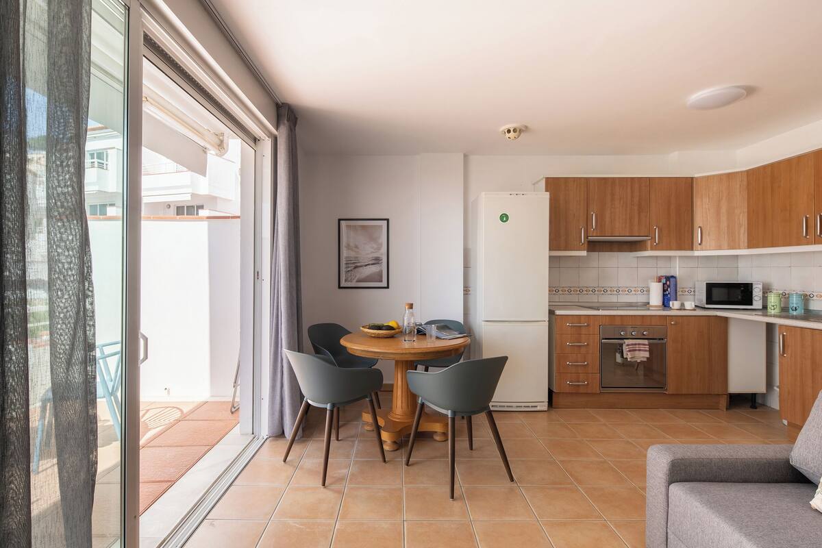 A compact kitchen with wooden cabinets, a microwave, and a small oven.