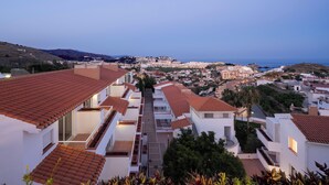 A coastal residential area with terracotta-tiled buildings, a clear view of the sea, and a hilly landscape in the background. - APARTAMENTOS TROPICALIA ALMUÑECAR (Almunecar)