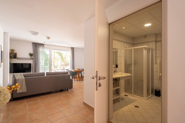 Un salon moderne comprenant un canapé, un coin repas et une salle de bain dotée d’une douche à parois de verre.