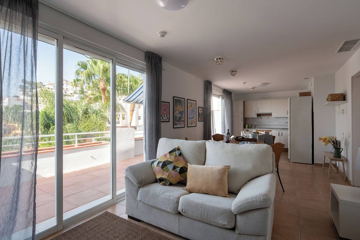 A living room with a sofa, a dining area, and a kitchen.