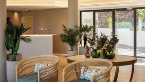 A reception area with wicker chairs, a round table, and potted plants. - APARTAMENTOS TROPICALIA ALMUÑECAR (Almunecar)