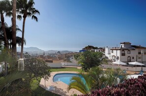 A residential area with a swimming pool, palm trees, and white houses with red-tiled roofs. - APARTAMENTOS TROPICALIA ALMUÑECAR (Almunecar)