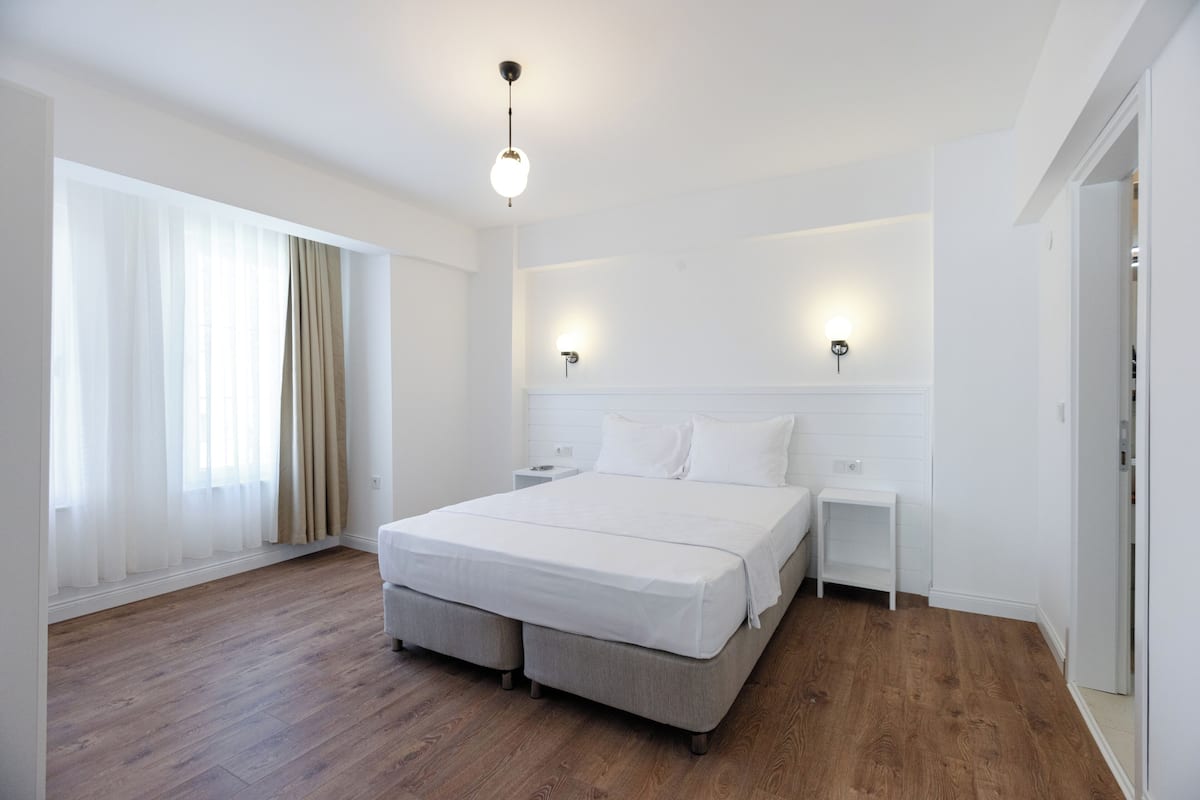Quarto moderno com uma cama grande, mesas de cabeceira e criado-mudo.