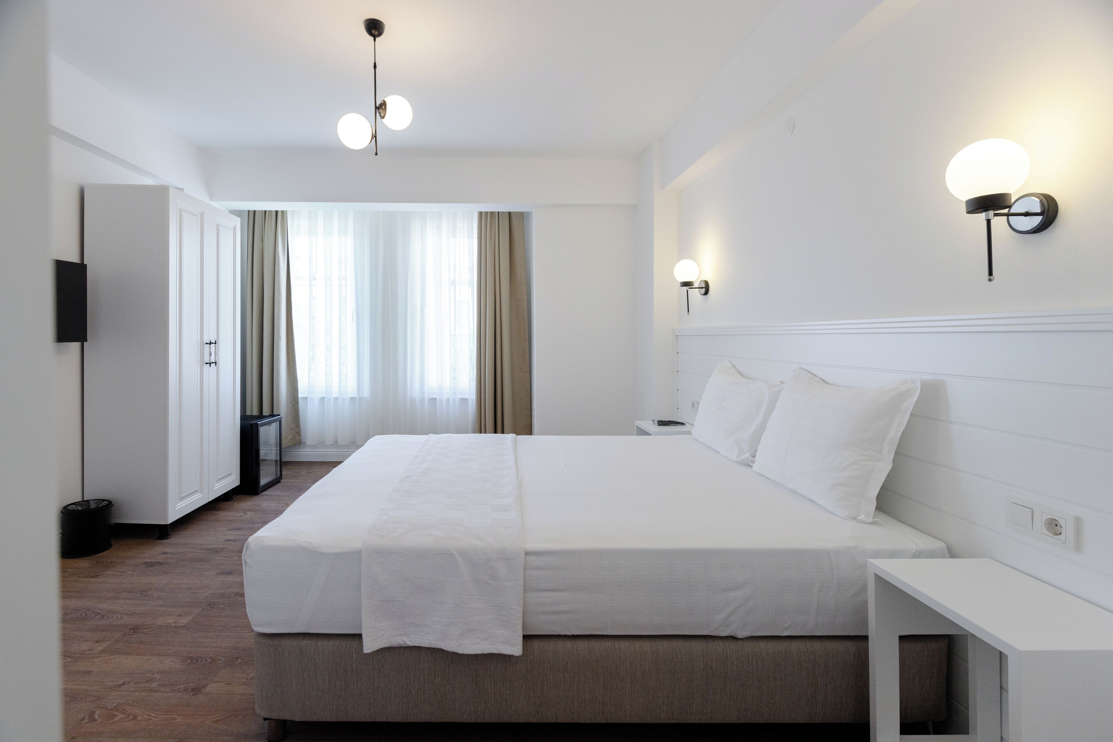 Habitación de hotel con una cama grande, mesitas de noche, un televisor de pantalla plana y vista al pasillo.