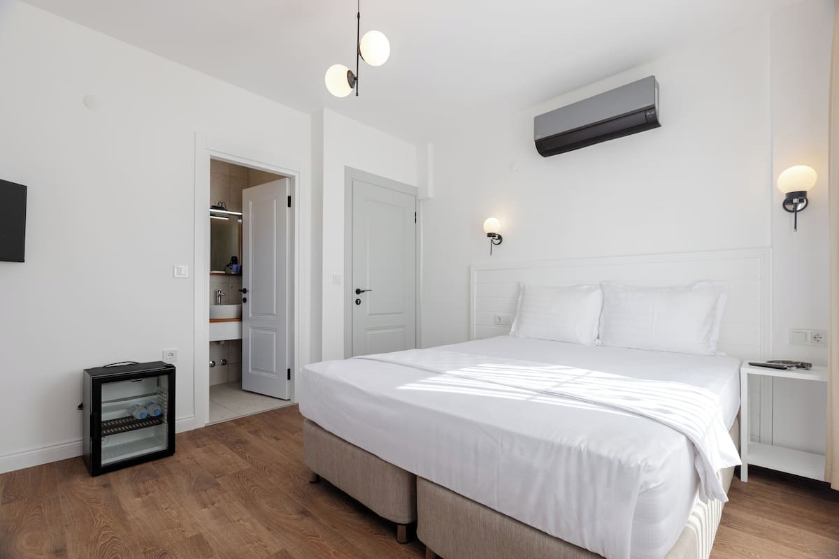 Quarto moderno com cama grande, closet espaçoso e pequena geladeira.