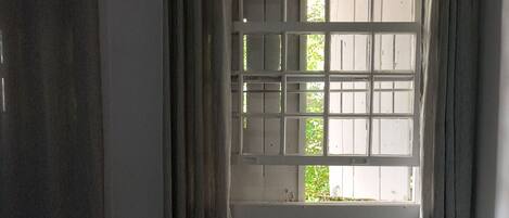 Una habitación con cama, escritorio, radiador y ventana con cortinas.