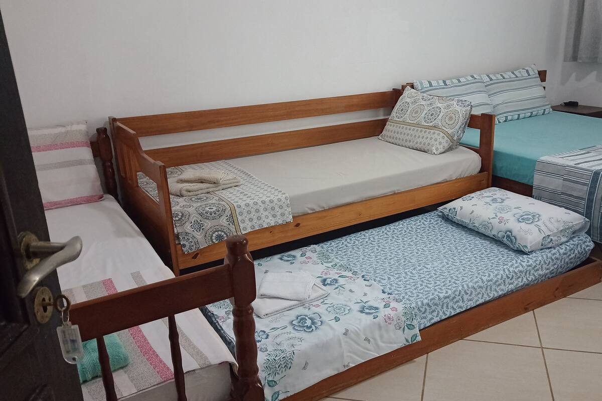A room with a wooden bed, a small table, and a chair.