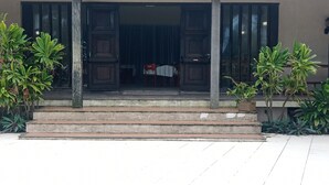 A building entrance with a set of concrete steps leading up to a door with glass panels. There are potted plants on either side of the entrance. - Mansão de Pirah  (Niteroi)