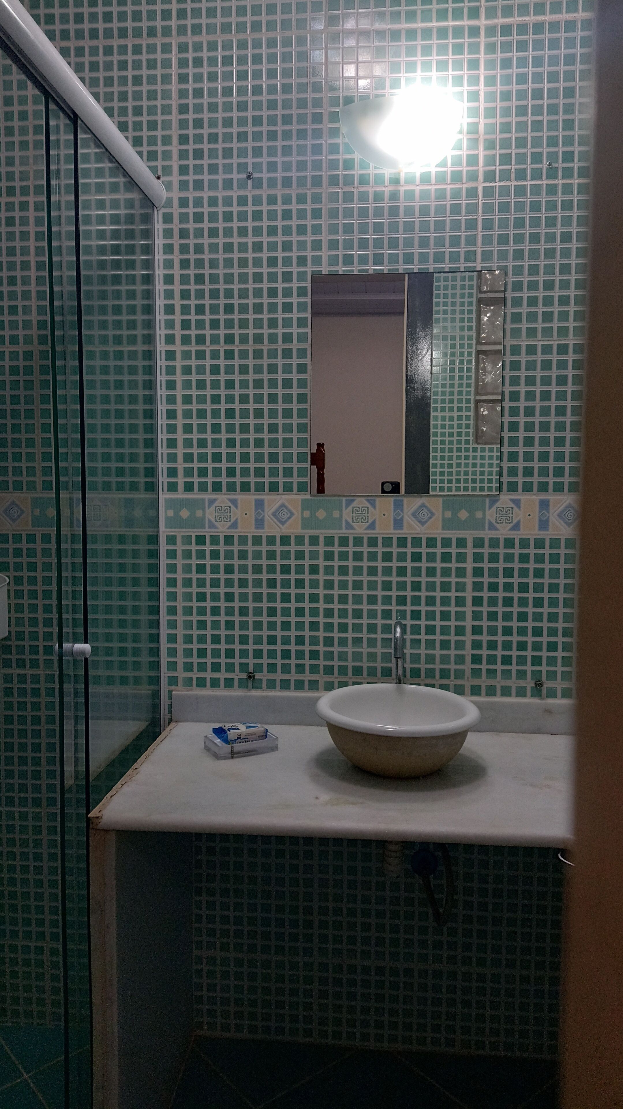 A bathroom with a sink, mirror, and tiled walls.