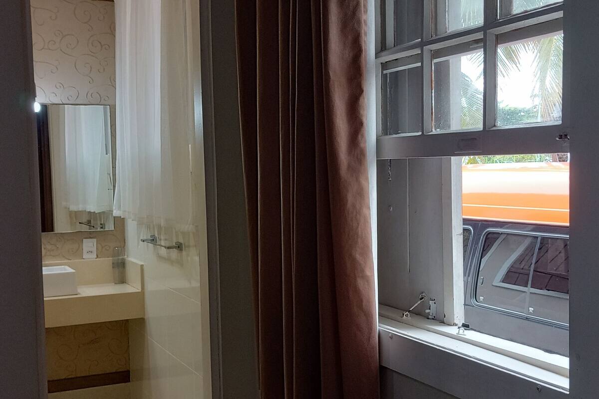 A bathroom with a sink, mirror, and window with curtains.