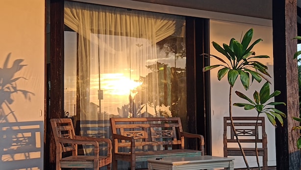 A room with a large window, two wooden chairs, a small table, and a potted plant. - Mansão de Pirah  (Niteroi)