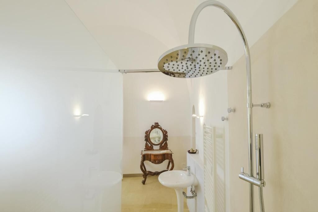 Un baño con ducha, lavamanos y tocador con espejo.