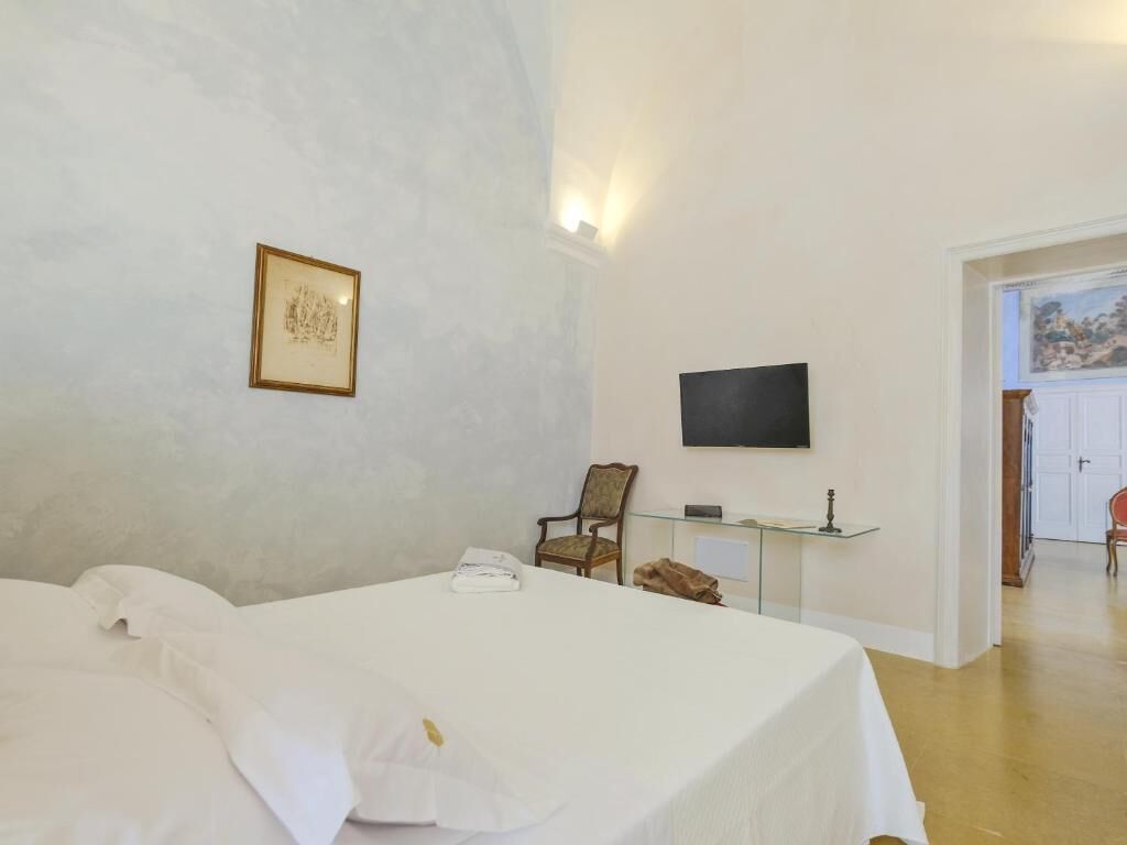 A hotel room with a bed, a desk, a chair, a television, and a framed picture on the wall.