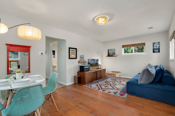 A dining area with a table set for four, a blue sofa, and a wooden floor.